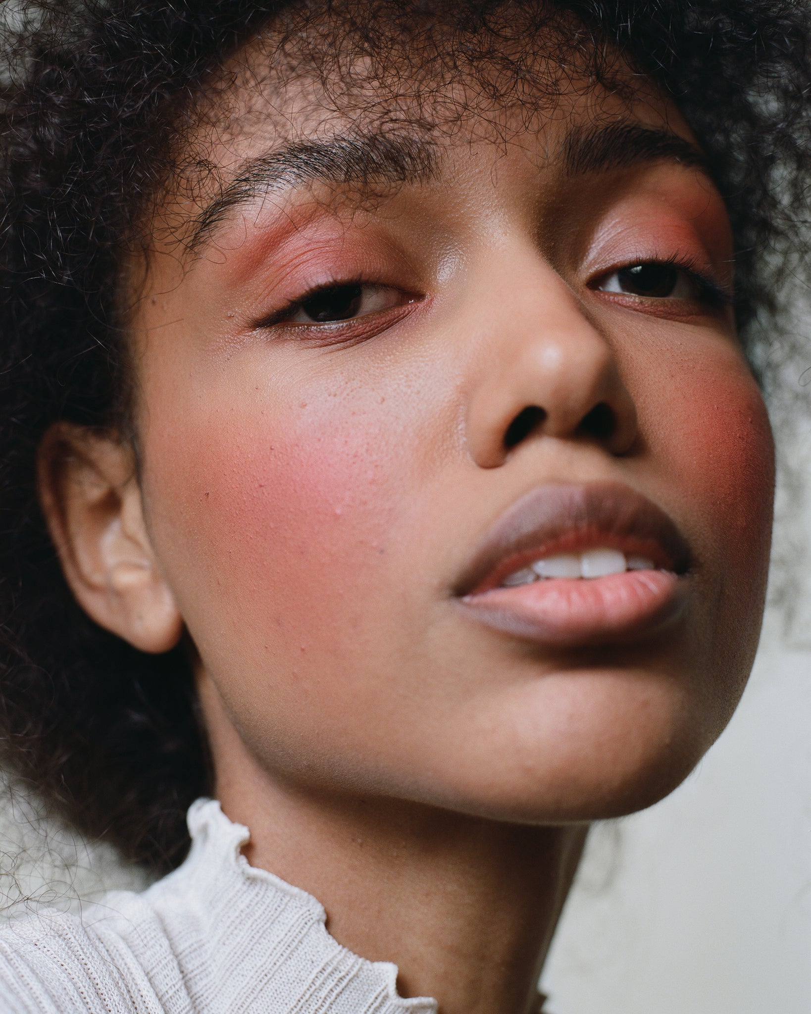 Model wearing MÁDARA Organic Skincare magnetic blush bare blossom on A6822 on skin; close-up portrait shows natural application results.