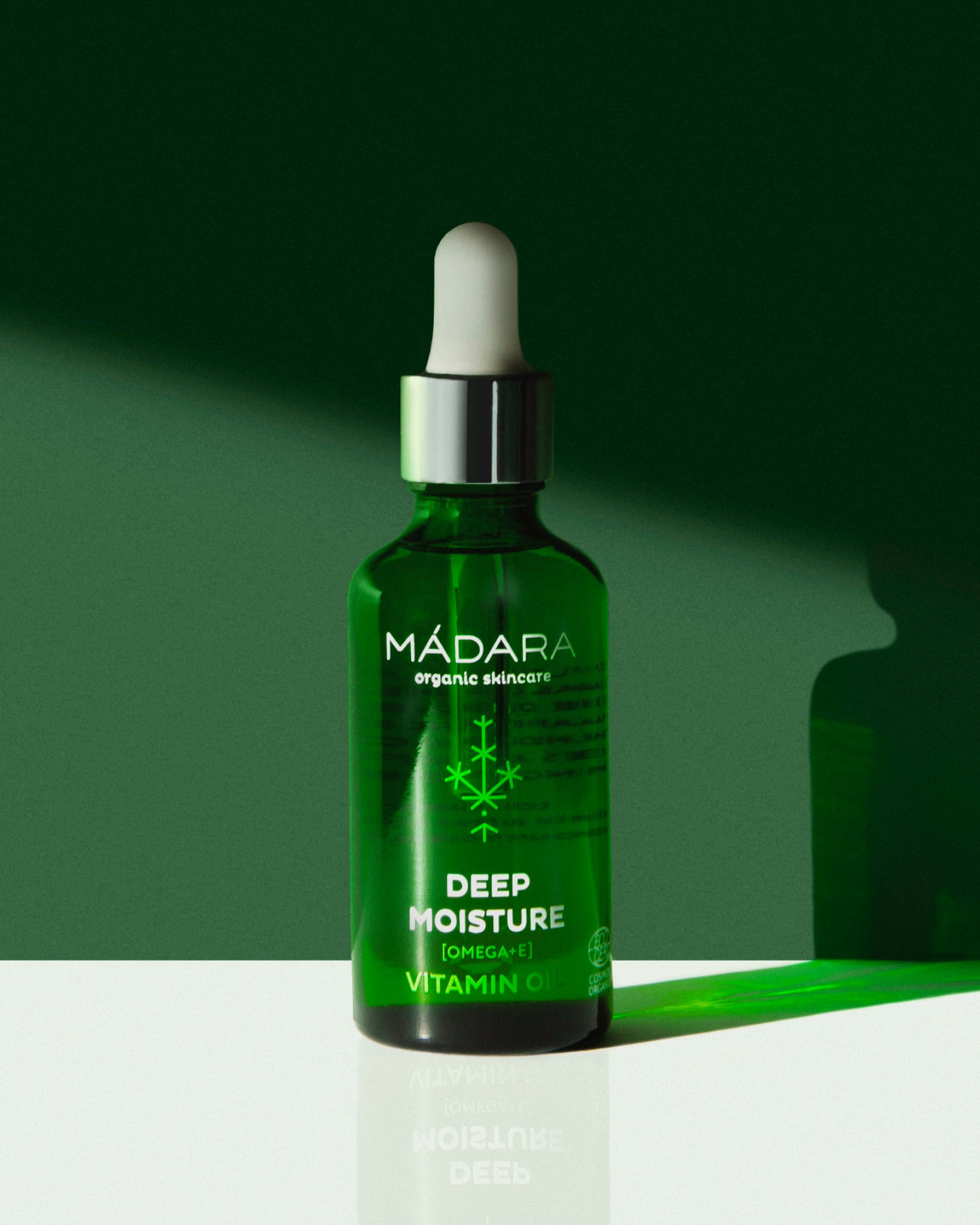 Model wearing MÁDARA Organic Skincare omega and vitamin e oil for face A2281 face oil on skin; close-up portrait shows natural application results.